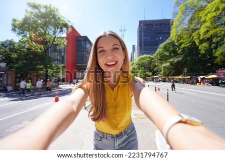 Tourism in Sao Paulo. Beautiful smiling girl takes self portrait on Paulista Avenue, Sao Paulo, Brazil. Royalty-Free Stock Photo #2231794767