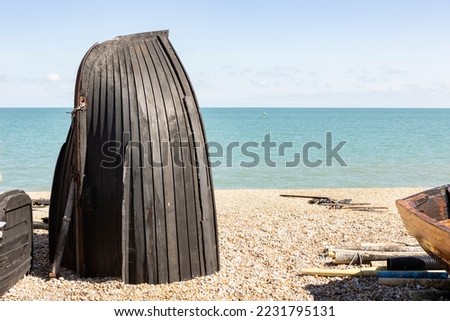 black boat hull on a pebble beach converted into a fishing storage area