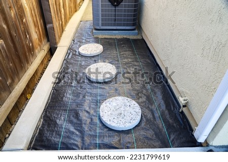 View of round stepping stones on top of heavy duty pp material for weed prevention. Hardscaping process. Royalty-Free Stock Photo #2231799619