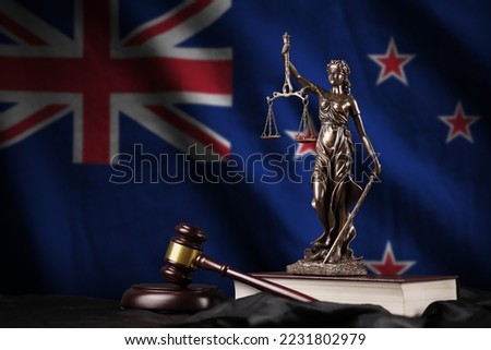 New Zealand flag with statue of lady justice, constitution and judge hammer on black drapery. Concept of judgement and punishment