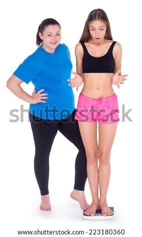 Fun picture of overweight woman discouraging thin young woman standing on weighs and measuring, isolated on white