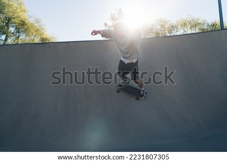 Full body of male skater performing stunt on ramp while practicing extreme riding improving skills during training at city skate park
