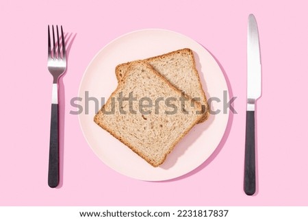 Flat lay of Whole wheat sandwich bread on plate, fork and knife on pink background