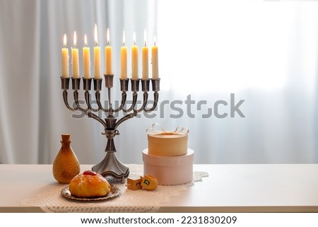Jewish holiday Hanukkah with menorah (traditional Candelabra), donuts and wooden dreidels (spinning top), chocolate coins.  Inscription on the menorah "Olive oil"