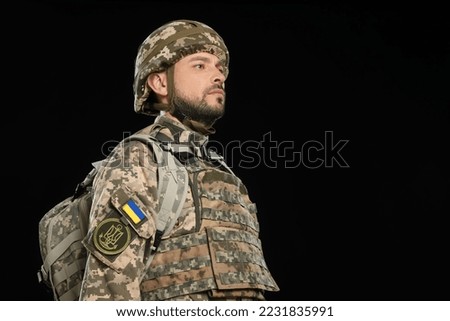 Soldier in Ukrainian military uniform with backpack on black background