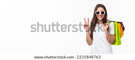 Shopping, leisure and lifestyle concept. Relaxed, carefree attractive modern feminine girl, holding shop bags behind shoulder and make peace sign, wear sunglasses, buying clothes for summer.