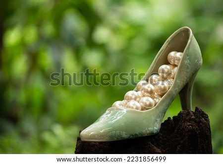 Old green ceramic shoe and pearl on nature background.