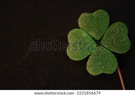 Green heart jelly candy arranged in clover leaves on black background.Concept for Valentine's day. 