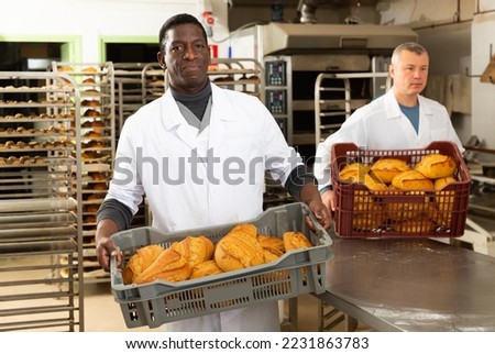 Portrait of two man bakery employees offering delicious bread in bakery. High quality photo