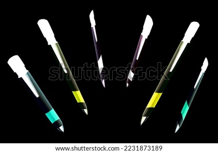 Pens with blue, yellow and white ink in the writing position on black background