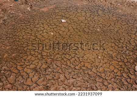 Cracked red soil ground Earth for texture background,desert cracks,Dry Orange surface Arid,drought land,Picture of natural disaster. drought land Caused by global warming and deforestation.