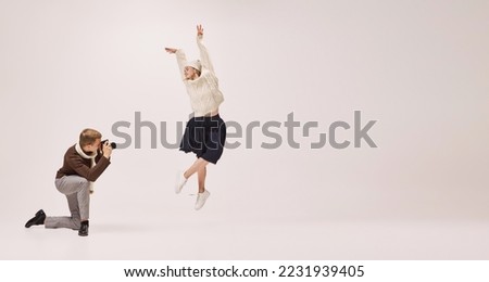 Ease of movement. Young stylish photographer taking picture of graceful young ballerina isolated on grey background. Retro, vintage, dance, holidays, party concept. Copy space for ad