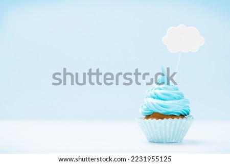 Blue cream cupcake with speech bubble decor on blue background with copy space
