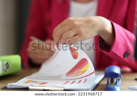 Female manager working with financial document on clipboard in office. Business woman correcting marketing data at her desk.