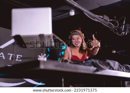 A female DJ and emcee making the shaka sign. A professional Disc jockey performing at a high end night club.