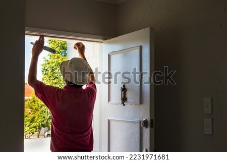 Man applying draught stopping foam tape to the door frame. Home maintenance to meet the healthy home standard. Auckland.  Royalty-Free Stock Photo #2231971681
