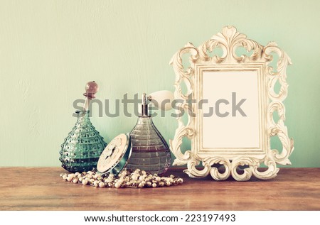 Vintage antique perfume bottles with old picture frame, on wooden table. retro filtered image 