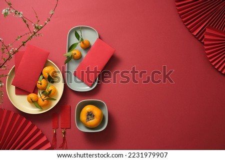 Fruits, lucky money, paper fan, and Lucky envelopes on a red background. Empty space for text. Chinese lunar new year. Top view Royalty-Free Stock Photo #2231979907