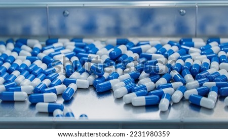 Blue Capsules on Conveyor at Modern Pharmaceutical Factory. Tablet and Capsule Manufacturing Process. Medical Drug Production Line.