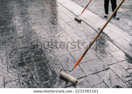 Coating concrete stamp floors Varnish. Stamp concrete texture pattern and background, and reflection of sunlight on the floor. Dark grey fresh stamp concrete. Royalty-Free Stock Photo #2231981561