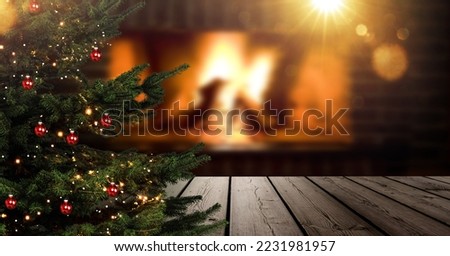 Christmas tree in foreground in front of blurred living room with fireplace
