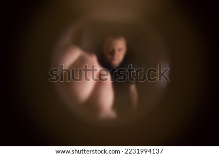 View from the peephole. Angry male neighbor knocking on the front door with his fist, close-up. Royalty-Free Stock Photo #2231994137