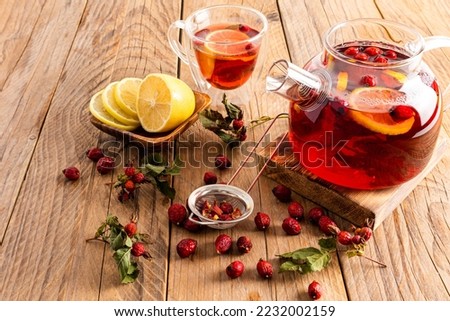 hot vitamin tea with rose hips stands on a wooden podium and a table with a cup of tea and lemon slices. phytotherapy. anti-cold drinks Royalty-Free Stock Photo #2232002159