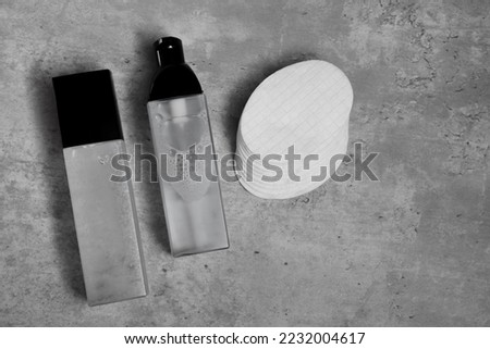 Luxury cosmetic products and cotton pads on grey table, flat lay. Space for text