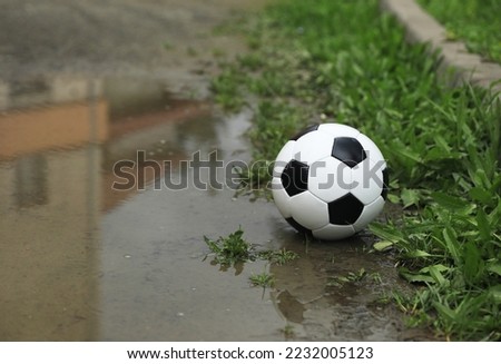 Soccer ball in puddle outdoors, space for text
