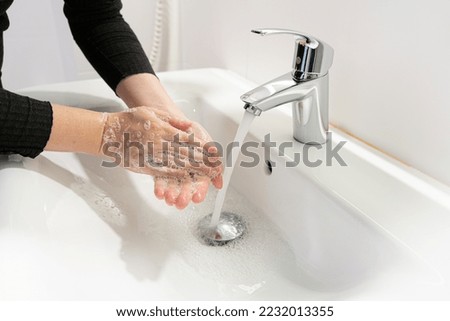 Washing hands with soap closeup. Woman wash her palms, soapy arms, washing hands on white blurred background, hygiene concept