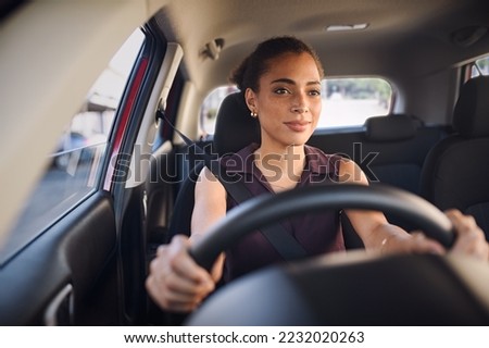 Smiling business woman driving car in city streets. Happy african american woman feeling comfortable sitting on driver seat in her new car. Mixed race girl with seat belt driving vehicle. Royalty-Free Stock Photo #2232020263