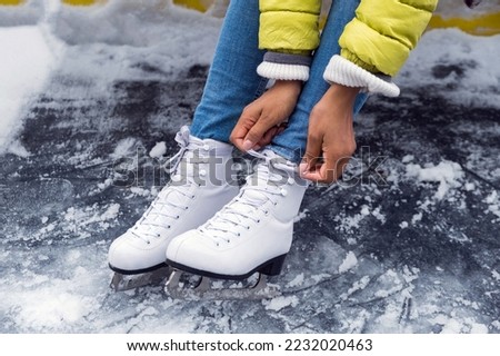 Close-up of African American woman tying shoelaces on ice skates before skating on the ice rink
