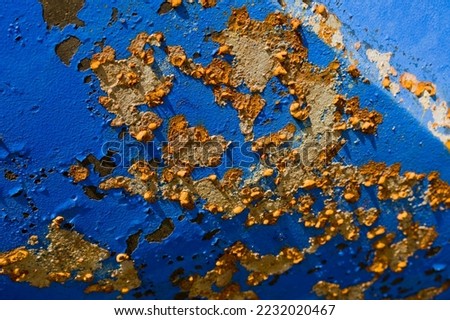 Yellow-brown rust spots and rust blisters have formed on the blue steel hull of a motorboat due to weathering and insufficient maintenance.