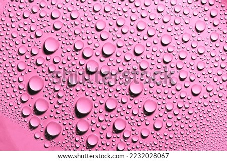 Detail and close up of condensation drops of pink water on surface. Texture background decoration.