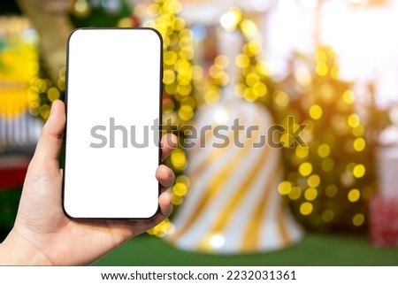Close-up of female use smartphone blurred images with Colorful balls on Green Christmas tree background Decoration During Christmas and New Year.