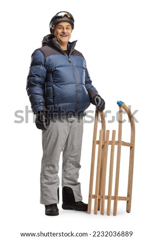 Mature man in winter clothes standing with a wooden sleigh isolated on white background