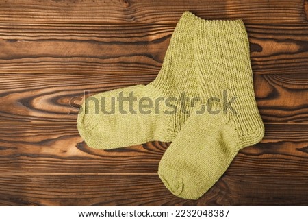 Bright handmade socks on a brown wooden background.Knitted warm, winter socks. Wool yarn. winter hobbies. Hobby.Place for text, space for copy.