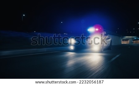 Traffic Patrol Car In Pursuit, Driving Fast with Sirens Blazing through the City Tunnel. Officers of the Law Chasing a Suspect. Cops in Squad Car React to Emergency Call. Cinematic Night Shot Royalty-Free Stock Photo #2232056187