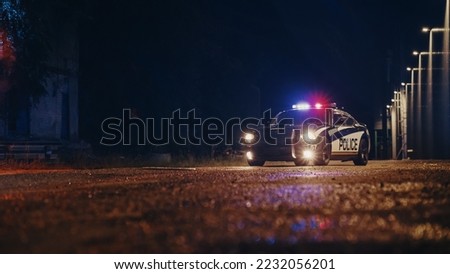 Low Angle Shot of a Stopped Police Car with Lights and Siren on During a Misty Night. Patrolling Vehicle on Stand by, Waiting for Orders to Start Pursuing Suspects. Police Enforcement Royalty-Free Stock Photo #2232056201