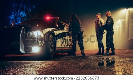 Two Police Officers Arrest Suspect, Put Him in the Backseat of Patrol Сar. Officers of the Law Detain, Handcuff Criminal. Cops Arresting Felon, Fight Crime. Cinematic Documentary Royalty-Free Stock Photo #2232056673