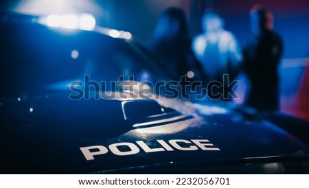 Cinematic Focus on Patrol Car: Two Police Officers Arrest Suspect, Put Him in Vehicle. Officers of the Law Handcuff Dangerous Criminal on Dark City Street. Cops Fight Crime. Documentary Shot Royalty-Free Stock Photo #2232056701