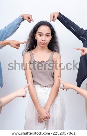 A young woman singled out by a mob. Arms from anonymous people pointing at her. Betrayed by her friends. Court of public opinion. Royalty-Free Stock Photo #2232057861