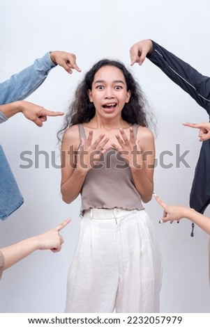 A scared woman singled out by a mob. Arms from anonymous people pointing at her. Accusation and trial concept. Court of public opinion. Royalty-Free Stock Photo #2232057979