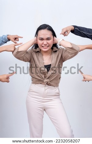 A young woman refuses to hear the bashers and accusers. Cracking under pressure. Arms from anonymous people pointing at her. Royalty-Free Stock Photo #2232058207