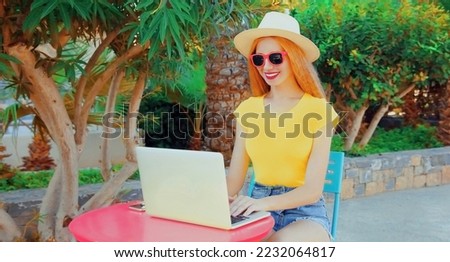 Young woman working with laptop while sitting at the table on summer vacation