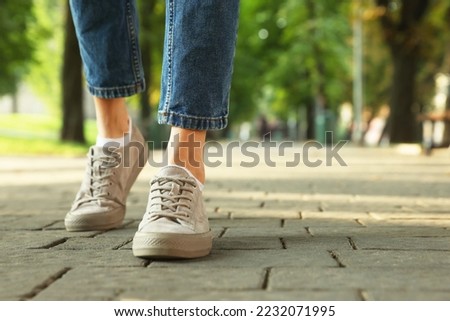 Woman in stylish sneakers walking on city street, closeup. Space for text Royalty-Free Stock Photo #2232071995