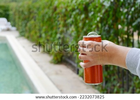 Woman holding tasty open canned beverage near swimming pool outdoors, closeup. Space for text