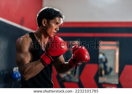 Asian active professional sport young man exercising in fitness gym. Attractive athlete sportsman workout by punching to sand bag to maintain strong muscle for health care in gym stadium or gymnasium. Royalty-Free Stock Photo #2232101785