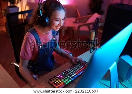 Joyful teenage girl playing videogame in her neon bedroom Royalty-Free Stock Photo #2232110697