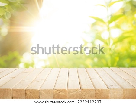 Selective focus of wood table top on blur green of tree in morning with sunny background.For create product display or design key visual layout.